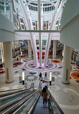 A large lobby with many floors and people on the escalators.